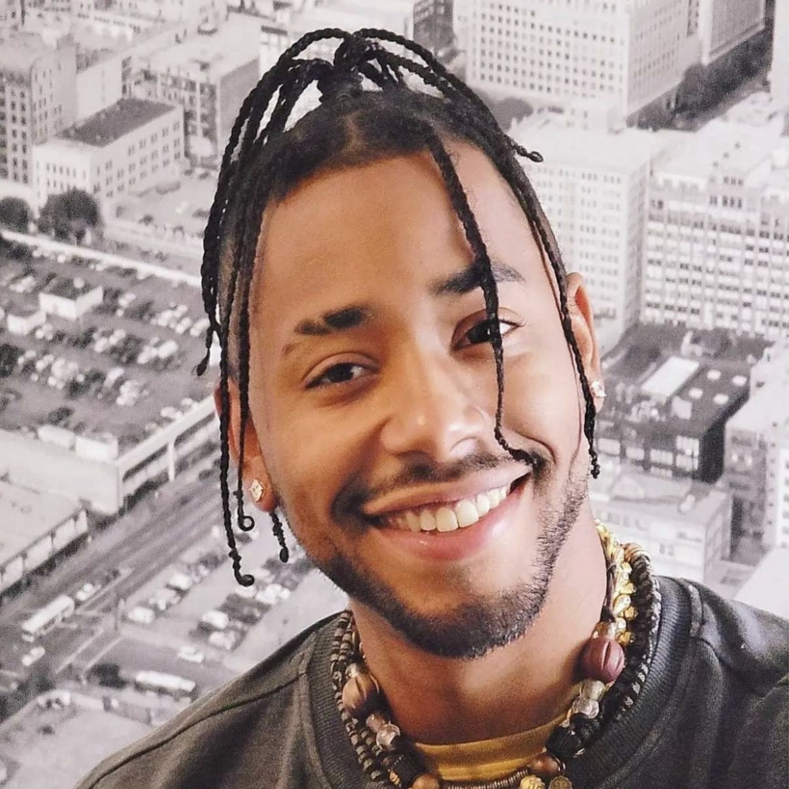 Arik Divine — braids and a smile before the city skyline