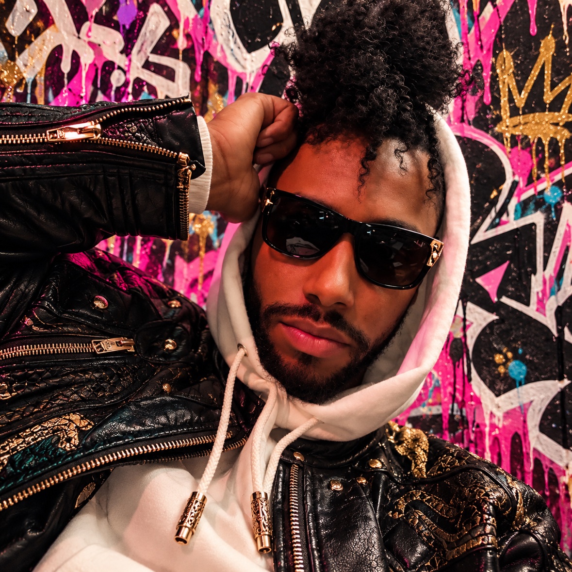 Arik Divine — leather and gold against the graffiti